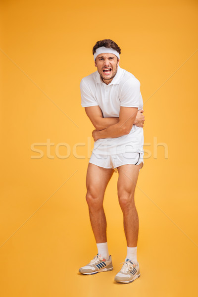Nieszczęśliwy młody człowiek sportowiec stałego ból brzucha żółty Zdjęcia stock © deandrobot