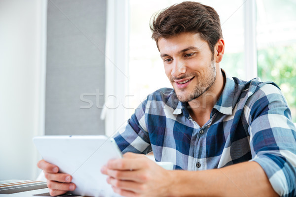 Sonriendo joven sesión tableta casa Foto stock © deandrobot