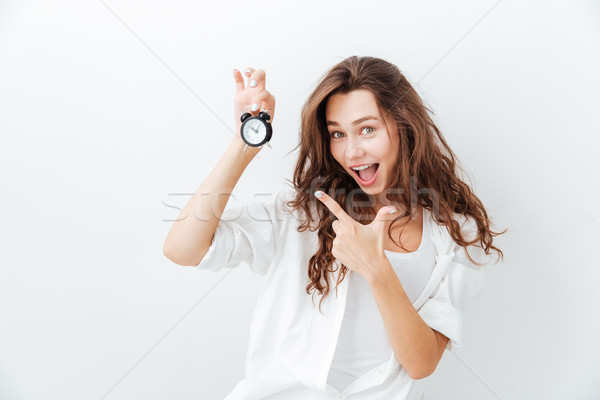 Happy playful young woman pointing at alam clock Stock photo © deandrobot