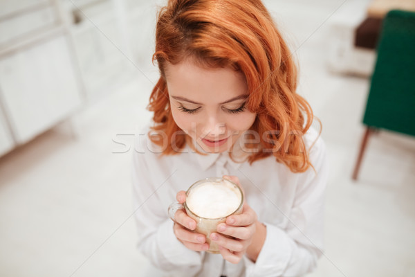 Redhead young beautiful woman drinking coffee in cafe. Stock photo © deandrobot