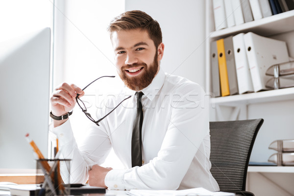 Cheerful young businessman sitting in office Stock photo © deandrobot