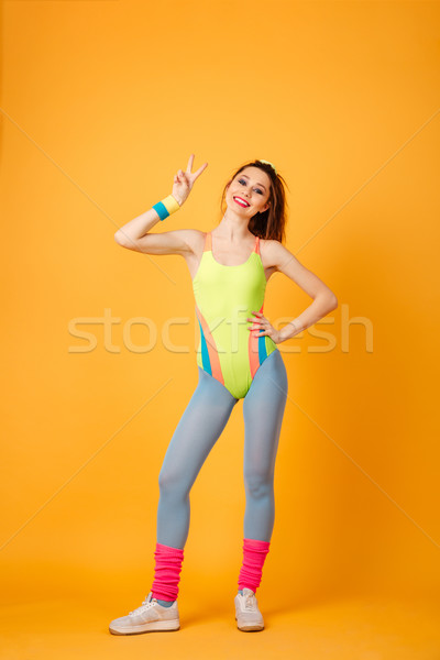 Cheerful attractive young woman athlete standing and showing peace sign Stock photo © deandrobot