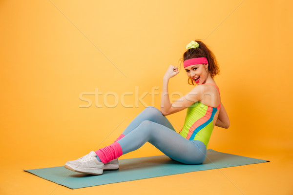 Smiling young sportswoman doing exercises for abdominal muscles on mat Stock photo © deandrobot