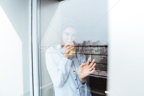 Pretty young lady standing at home looking at window Stock photo © deandrobot