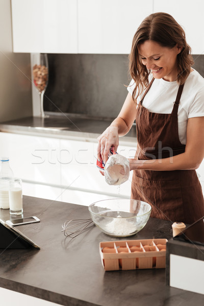 Vertical image of smiling casual woman cooking near the table Stock photo © deandrobot