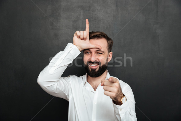 Portrait of sarcastic man showing loser sign on his forehead and Stock photo © deandrobot