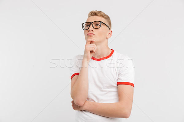 Image of thoughtful male student wearing eyeglasses looking upwa Stock photo © deandrobot