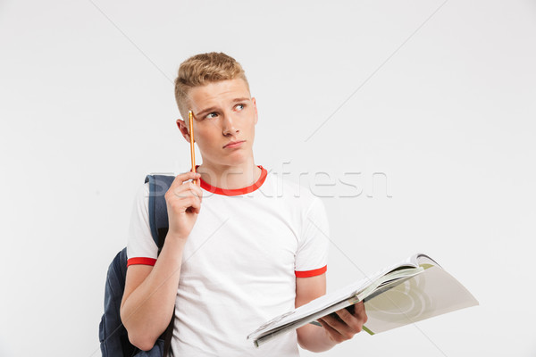 Image of sad smarty guy wearing backpack thinking and touching t Stock photo © deandrobot