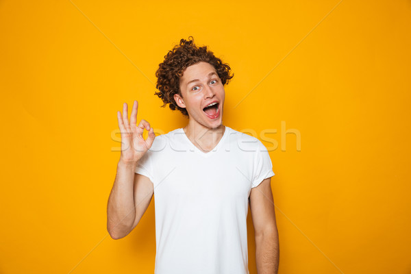 Portrait of a smiling curly haired man showing ok Stock photo © deandrobot