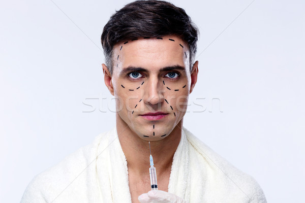 Attractive man at plastic surgery with syringe in his face Stock photo © deandrobot