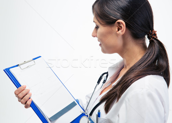 Female doctor reading notes on clipboard  Stock photo © deandrobot