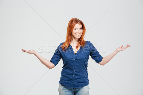 Happy woman holding copyspace on both palms over white background Stock photo © deandrobot