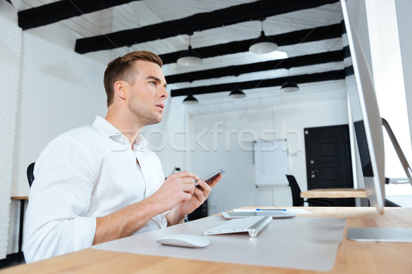 Businessman using computer and mobile phone at workplace Stock photo © deandrobot