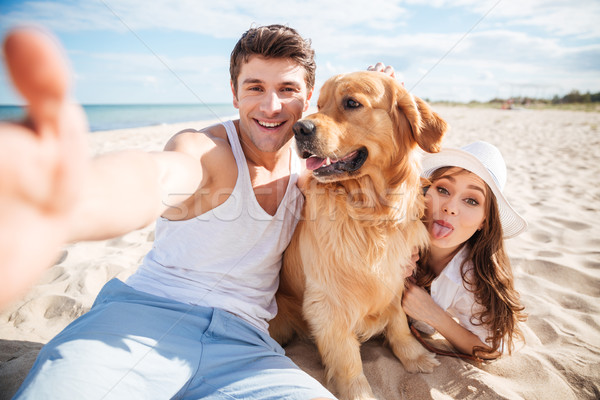 Happy couple with dog taking a selfie at the beach Stock photo © deandrobot