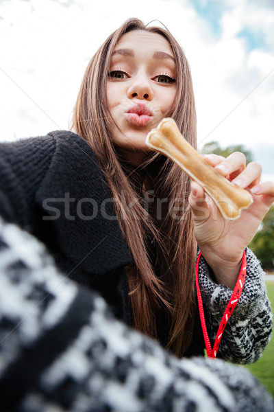 Woman showing bone and sending kiss to her dog outdoors Stock photo © deandrobot