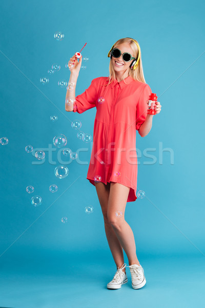 Woman in sunglasses blowing bubbles and listening music with headphones Stock photo © deandrobot