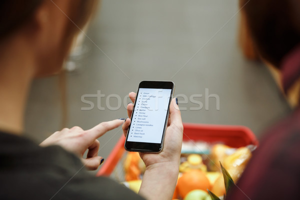 Loving couple in supermarket looking at list of purchases Stock photo © deandrobot