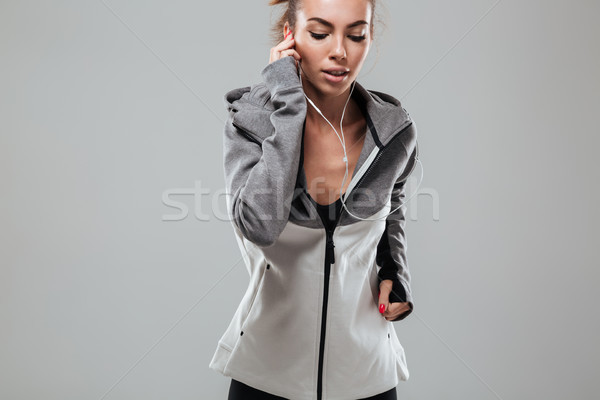 Young female runner in warm clothes running and listening music Stock photo © deandrobot