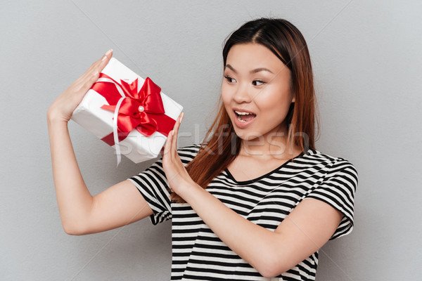 Surprised young woman holding gift. Stock photo © deandrobot