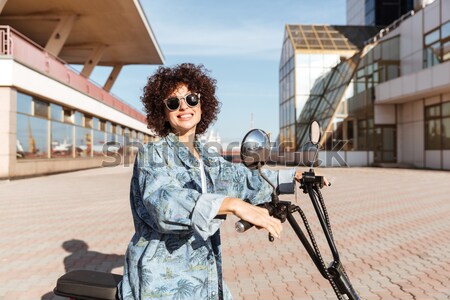Image of happy curly woman in sunglasses sitting on motorbike Stock photo © deandrobot