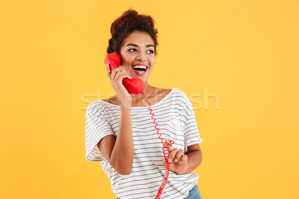Cheerful lady talking on red telephone and looking aside Stock photo © deandrobot