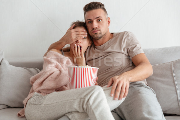 Stock photo: Portrait of a scared young couple eating popcorn