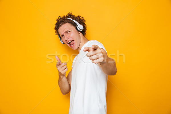 Photo of handsome caucasian guy with curly hair listening to mus Stock photo © deandrobot