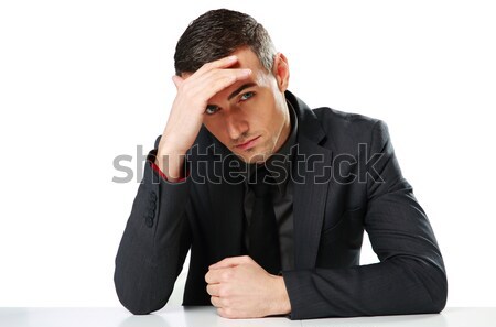 Stock photo: Pensive businessman sitting at the table isolated on a white background