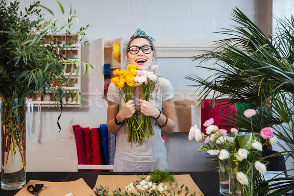 Happy woman florist with bunch of flowers standing and laughing Stock photo © deandrobot