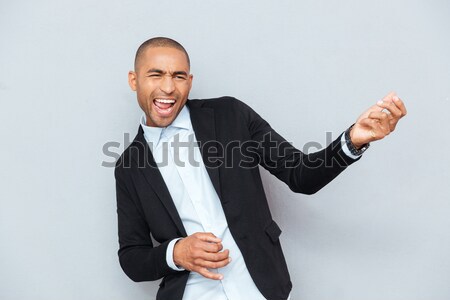 Attractive man taking his jacket off over gray background Stock photo © deandrobot