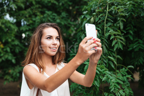 Young beautiful brunette woman making selfie with smartphone outdoors Stock photo © deandrobot