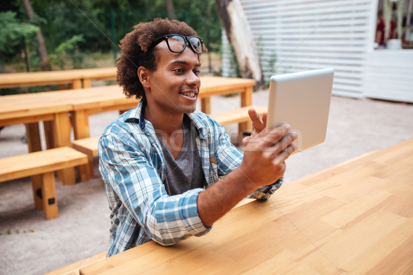 Cheerful african young man using tablet outdoors Stock photo © deandrobot