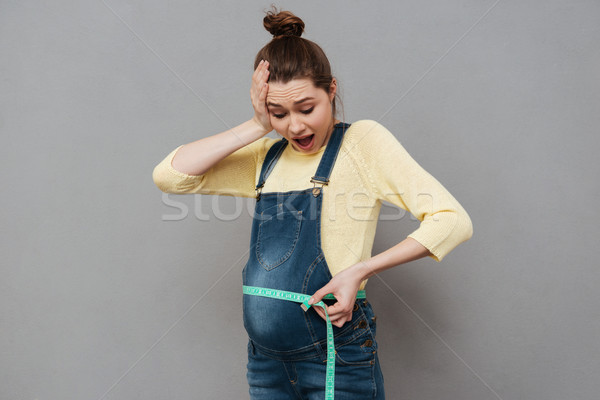 Pregnant shocked woman with centimeter Stock photo © deandrobot