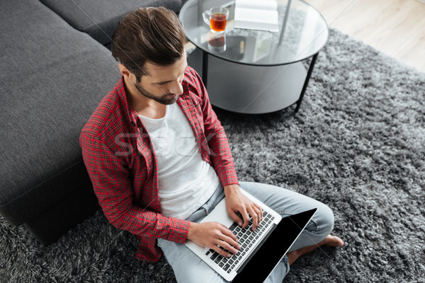 молодым человеком сидят домой используя ноутбук компьютер Сток-фото © deandrobot