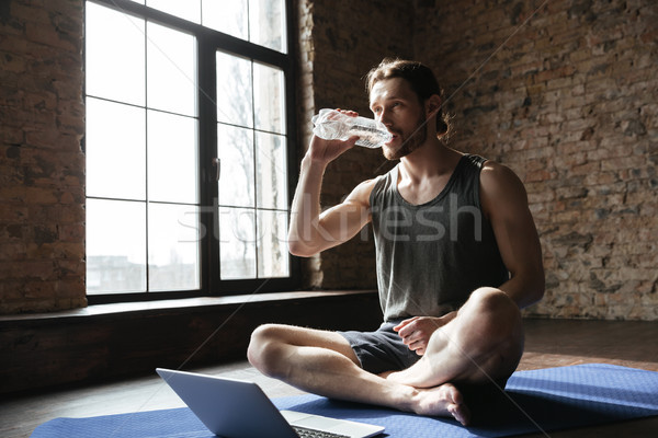 Sportsman in gym sitting on floor drinking water Stock photo © deandrobot