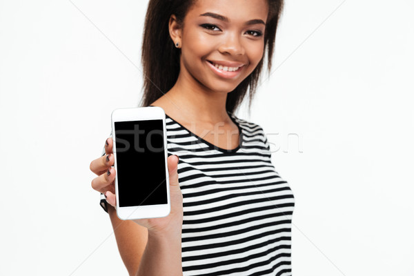 Cheerful young african woman showing display of phone. Stock photo © deandrobot