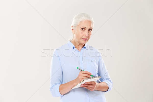 Confident serious woman writing in notebook isolated Stock photo © deandrobot
