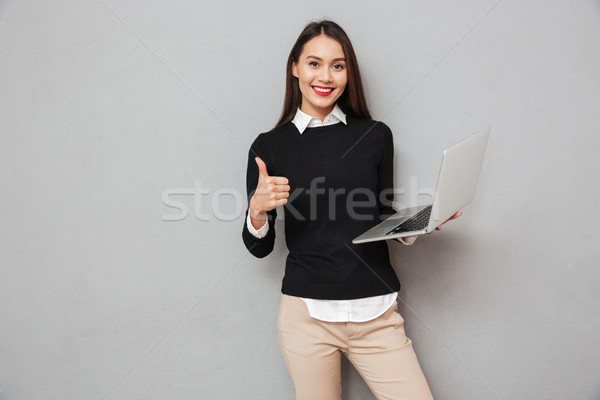 Pleased asian woman in business clothes holding laptop computer Stock photo © deandrobot