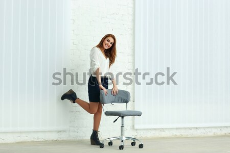 Young cheerful businesswoman sitting on the chair in office Stock photo © deandrobot