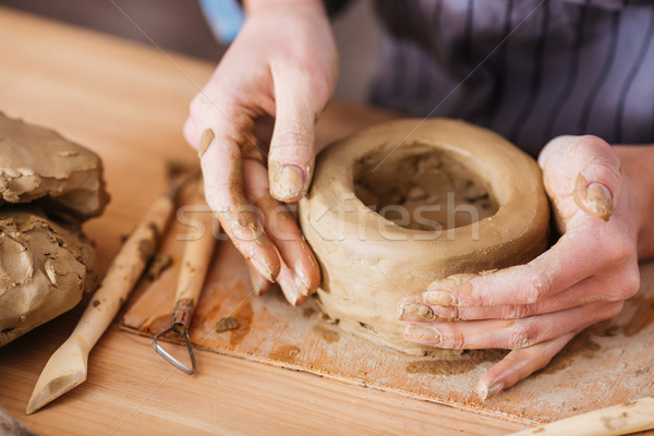 Hands of young woman making earthen pot on wooden table Stock photo © deandrobot