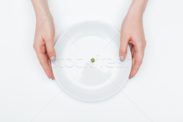 Stock photo: Plate with one green pea holded by hands of woman