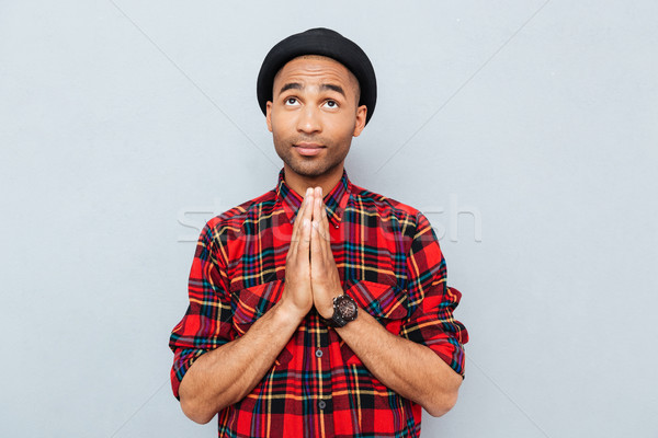 Handsome african american man in black hat standing and praying Stock photo © deandrobot