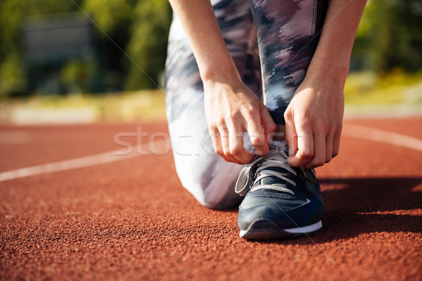 Closeup portrait of a young woman tying sneakers Stock photo © deandrobot