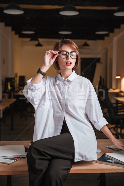 Seductive businesswoman sitting and posing on the table in office Stock photo © deandrobot