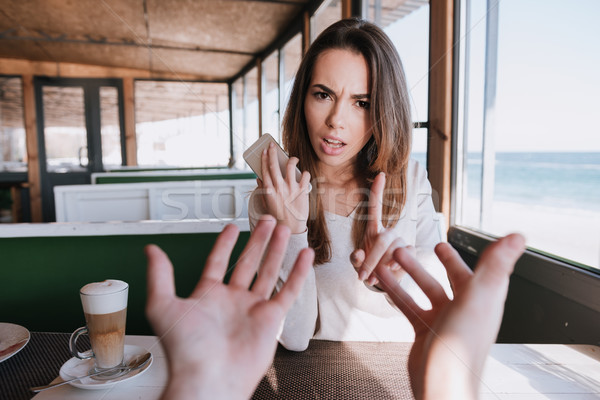 Displeased Woman on date with man talking at phone Stock photo © deandrobot