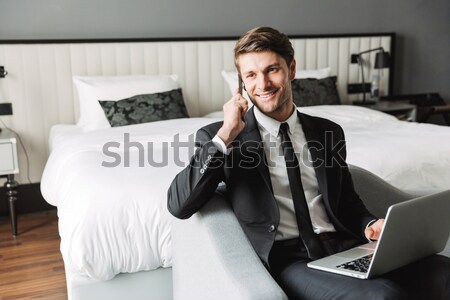 Cheerful businessman talking by phone and make winner gesture. Stock photo © deandrobot