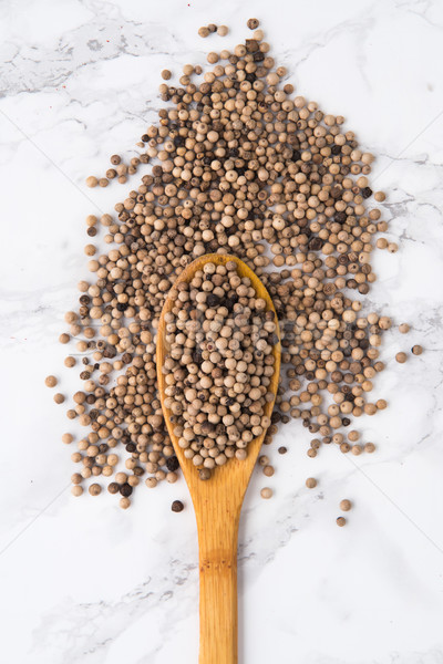Top view of a wooden spoon full of white peppercorns Stock photo © deandrobot