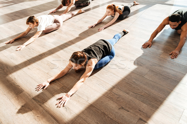 Multiethnic group of people doing stretching exercises in yoga studio Stock photo © deandrobot