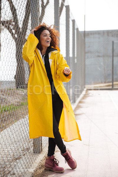 Amazing african curly young lady wearing yellow coat Stock photo © deandrobot