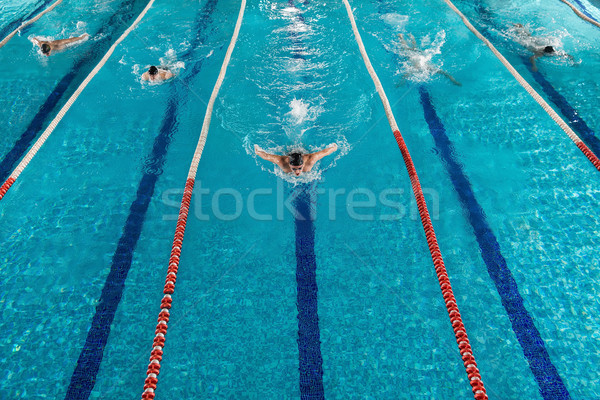 Five swimmers racing against each other in a swiming pool Stock photo © deandrobot